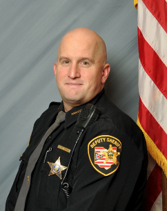 Robert-Mead officer-wearing-uniform-sitting-in front of American Flag